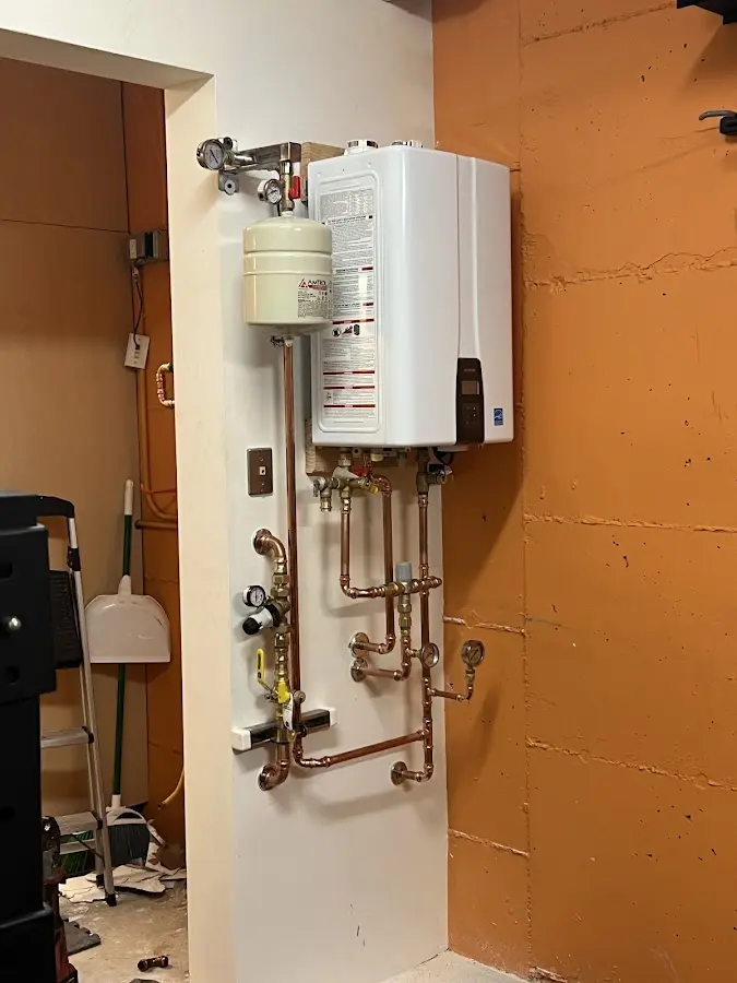 Plumbing technician inspecting water heater connections in Raton